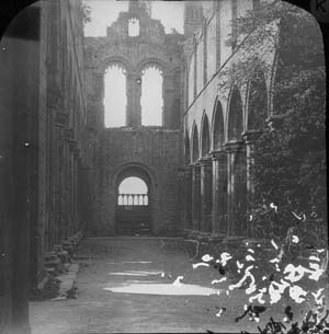 View along the nave of the church at Kirkstall Abbey looking west. Trees can be seen growing in the gap created by the partial collapse of the tower in 1779 on the right. The photograph must, therefore, have been taken prior to the the programme of conservation in 1892-6 when this damage was repaired.